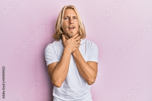 Caucasian young man with long hair wearing casual white t shirt shouting and suffocate because painful strangle. health problem. asphyxiate and suicide concept.