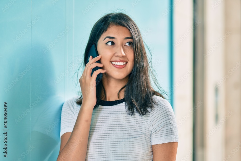 Young hispanic woman smiling happy talking on the smartphone at the city. Young hispanic woman smiling happy talking on the smartphone at the city.