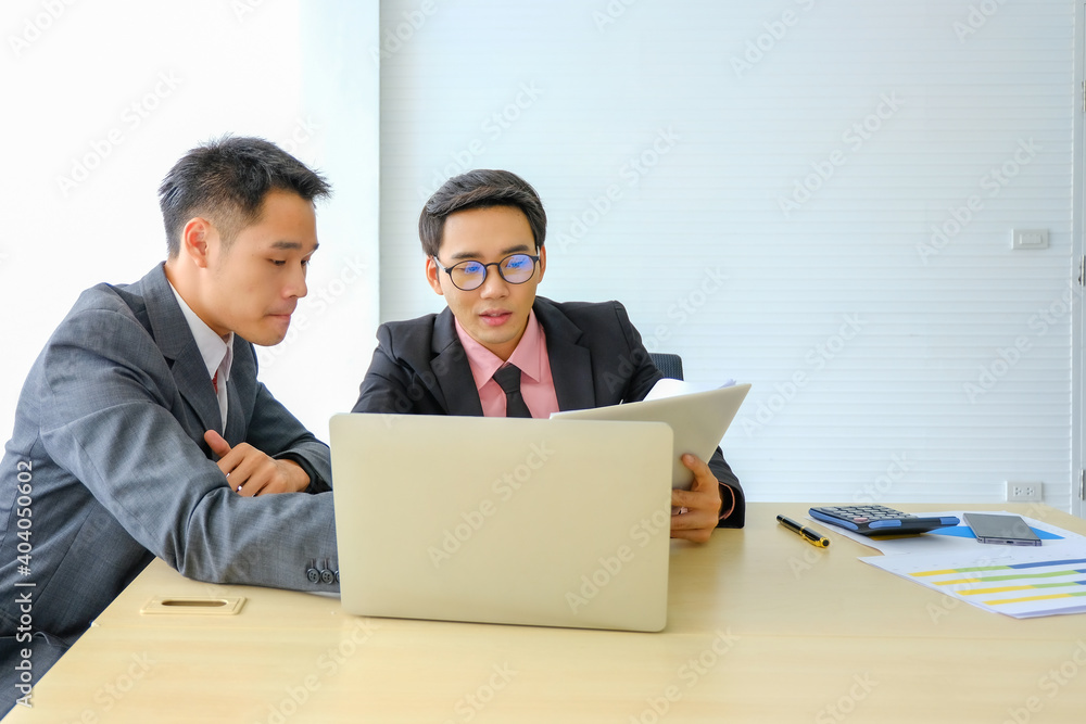 Two businessmen sitting at desk and discussing business matters. Business executives working in their office,The business has a problem,be serious Two businessmen sitting at desk and discussing business matters. Business executives working in their office,The business has a problem,be serious