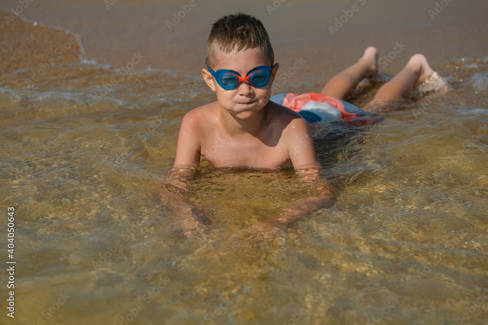 Children on the ocean. A young boy in goggles swimming in the sea. Kid on vacation. Family travel. Learning to swim.