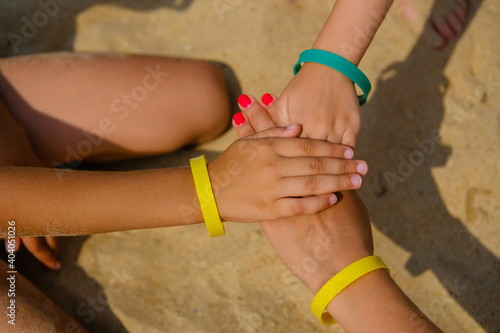 Family wearing color entrance wristbands of hotel resort or entertainment park at sand sea background.