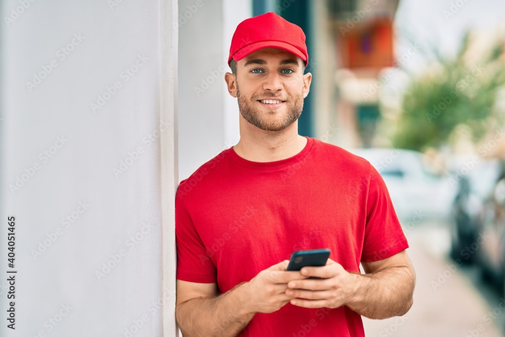 Young caucasian deliveryman smiling happy using smartphone at the city. Young caucasian deliveryman smiling happy using smartphone at the city.