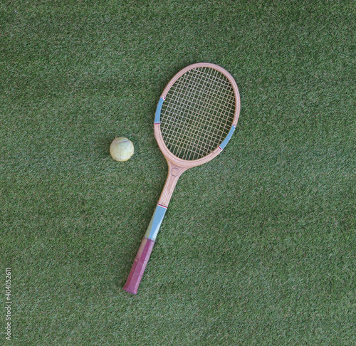old wooden tennis racket isolated on green grass © serikbaib