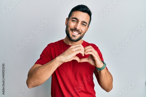 Young hispanic man wearing casual clothes smiling in love doing heart symbol shape with hands. romantic concept.