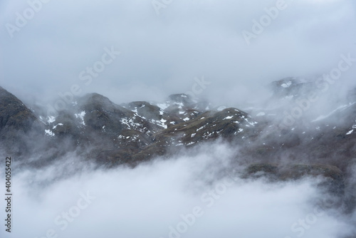 Epic Winter landscape image of view from Side Pike towards Langdale pikes with low level clouds on mountain tops and moody mist swirling around © veneratio