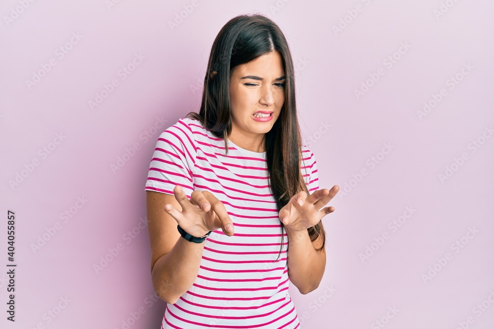Young brunette woman wearing casual clothes over pink background disgusted expression, displeased and fearful doing disgust face because aversion reaction. Young brunette woman wearing casual clothes over pink background disgusted expression, displeased and fearful doing disgust face because aversion reaction.