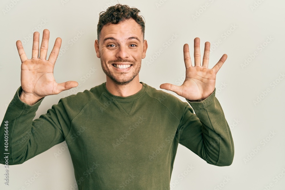 Fototapeta premium Young hispanic man wearing casual clothes showing and pointing up with fingers number ten while smiling confident and happy.