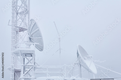 frosty parabolic antennas and the basement of the cell tower on the base radio station located in the highlands