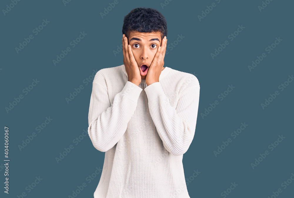Young african amercian man wearing casual clothes afraid and shocked, surprise and amazed expression with hands on face Young african amercian man wearing casual clothes afraid and shocked, surprise and amazed expression with hands on face