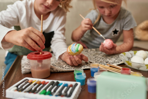 Photography Close up of hands of adorable little boy painting colorful Easter eggs together