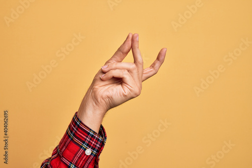 Photos Hand of caucasian young man showing fingers over isolated yellow background snap