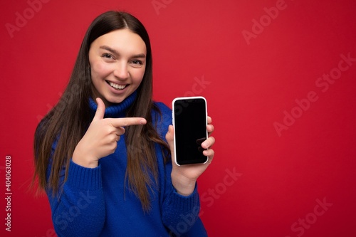 Photo of beautiful smiling young woman good looking wearing casual stylish outfit standing isolated on background with copy space holding smartphone showing phone in hand with empty screen display for © Ivan Traimak