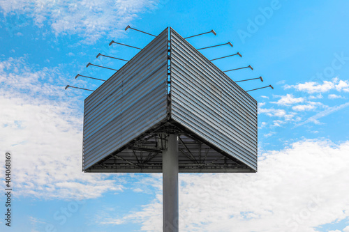 Advertising billboard against blue cloudy sky. Two empty surfaces are at an angle to each other. Different viewing planes. The lack of advertising, empty areas, the economic slowdown, lockdown concept