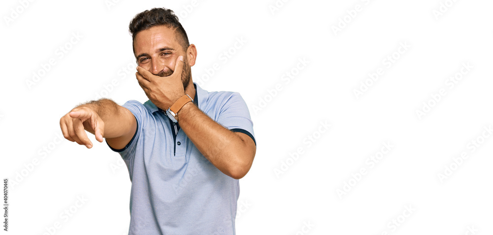 Handsome man with beard wearing casual clothes laughing at you, pointing finger to the camera with hand over mouth, shame expression Handsome man with beard wearing casual clothes laughing at you, pointing finger to the camera with hand over mouth, shame expression