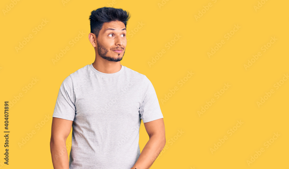 Handsome latin american young man wearing casual tshirt smiling looking to the side and staring away thinking. Handsome latin american young man wearing casual tshirt smiling looking to the side and staring away thinking.