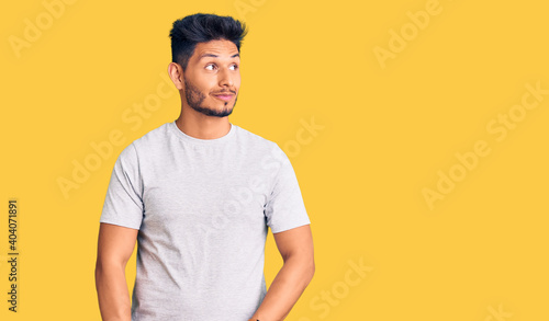 Fotografi Handsome latin american young man wearing casual tshirt smiling looking to the side and staring away thinking