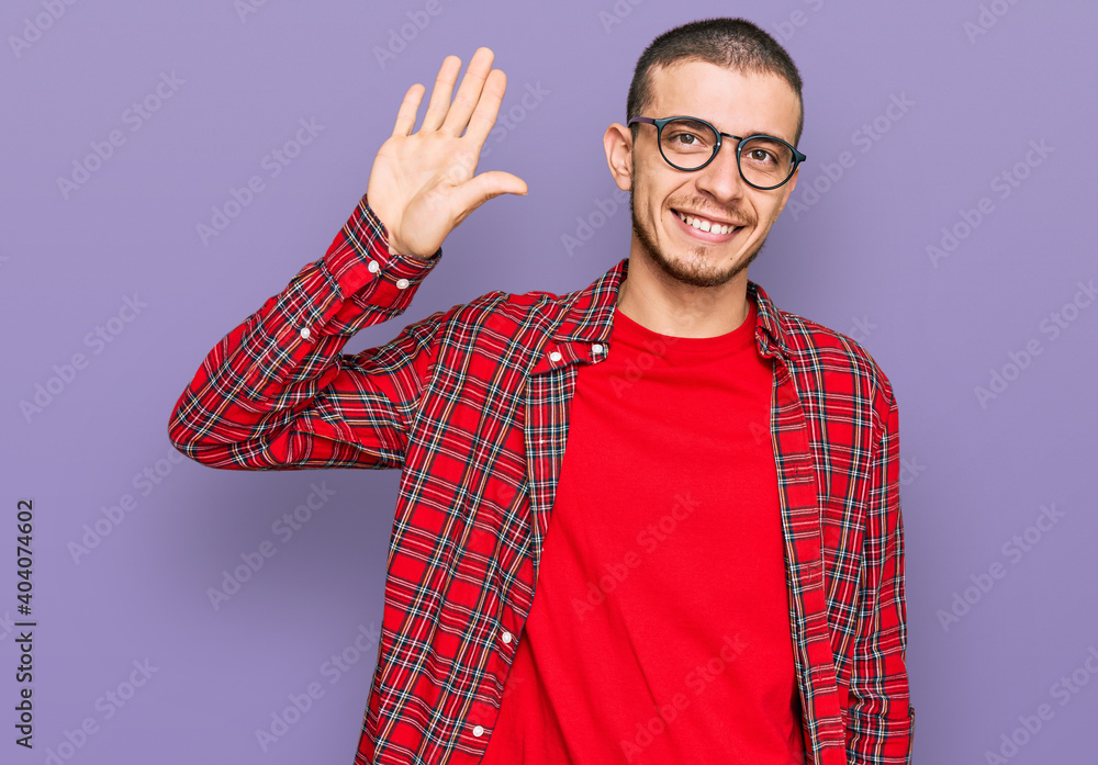 Hispanic young man wearing casual clothes waiving saying hello happy and smiling, friendly welcome gesture Hispanic young man wearing casual clothes waiving saying hello happy and smiling, friendly welcome gesture