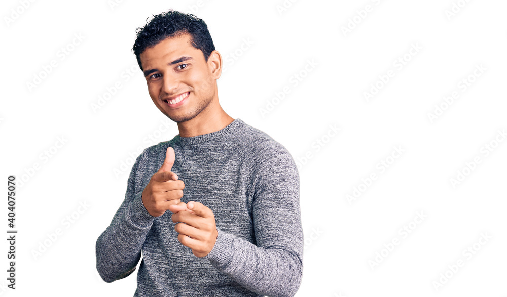 Hispanic handsome young man wearing casual sweater pointing fingers to camera with happy and funny face. good energy and vibes. Hispanic handsome young man wearing casual sweater pointing fingers to camera with happy and funny face. good energy and vibes.