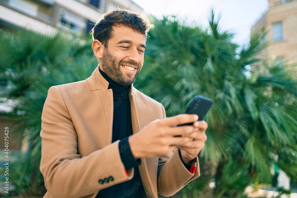 Handsome business man wearing elegant jacket using smartphone smiling happy outdoors Handsome business man wearing elegant jacket using smartphone smiling happy outdoors