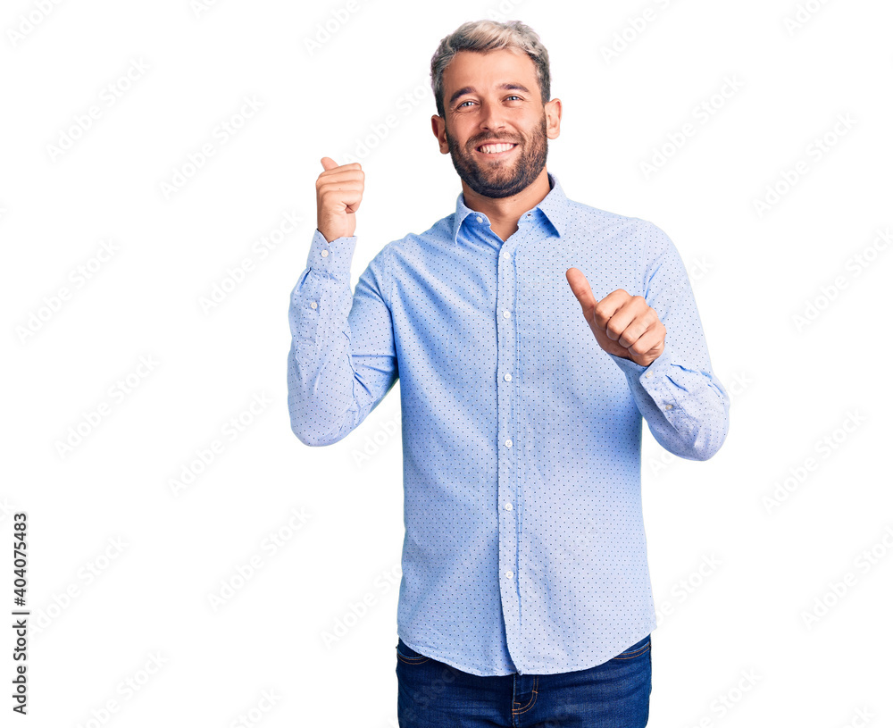 Young handsome blond man wearing elegant shirt pointing to the back behind with hand and thumbs up, smiling confident Young handsome blond man wearing elegant shirt pointing to the back behind with hand and thumbs up, smiling confident