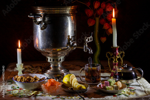 Evening tea from a samovar by candlelight with lemon and sweets.