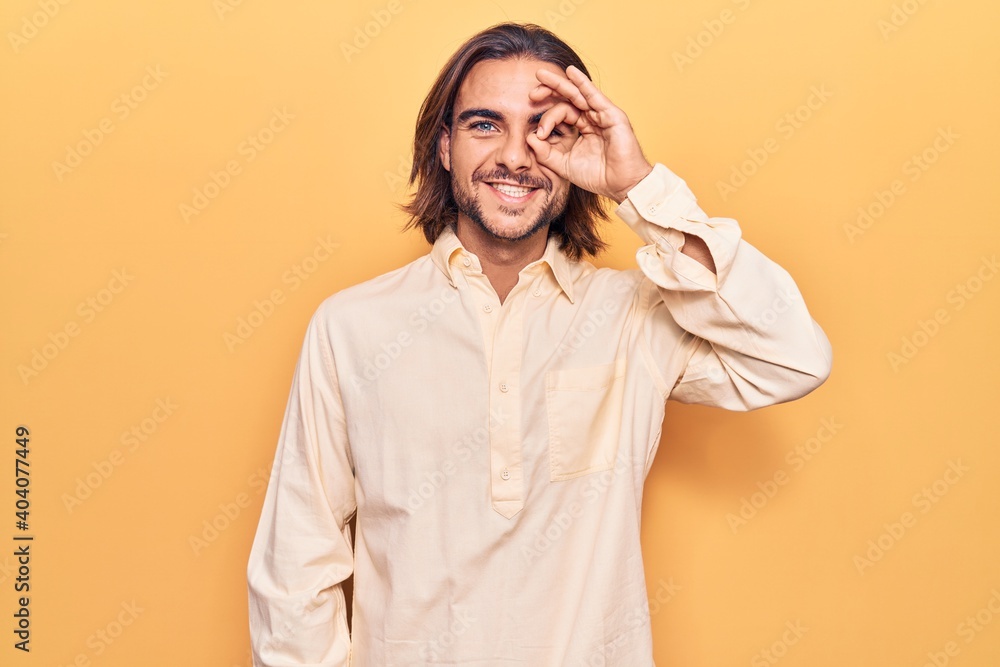 Young handsome man wearing business clothes doing ok gesture with hand smiling, eye looking through fingers with happy face.