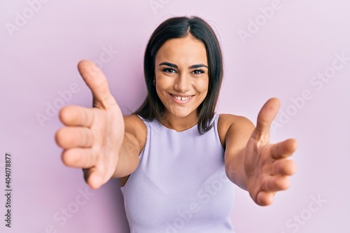 Young brunette woman wearing casual clothes looking at the camera smiling with open arms for hug. cheerful expression embracing happiness. © Krakenimages.com