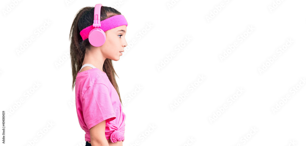 Cute hispanic child girl wearing gym clothes and using headphones looking to side, relax profile pose with natural face with confident smile. Cute hispanic child girl wearing gym clothes and using headphones looking to side, relax profile pose with natural face with confident smile.