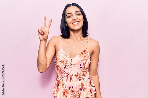 Young beautiful latin woman wearing casual clothes showing and pointing up with fingers number two while smiling confident and happy.