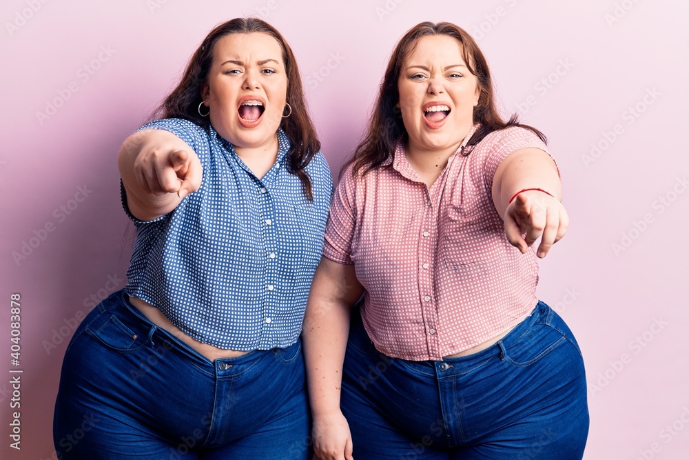 Fototapeta premium Young plus size twins wearing casual clothes pointing displeased and frustrated to the camera, angry and furious with you