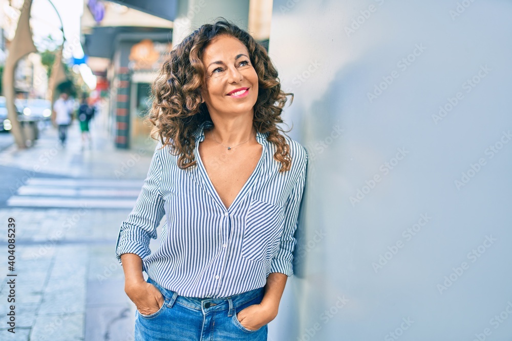 © Krakenimages.com - Middle age hispanic woman smiling happy leaning on the wall at the city. © Krakenimages.com - Middle age hispanic woman smiling happy leaning on the wall at the city.