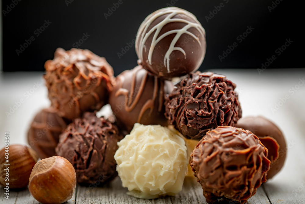 Mixed chocolate gourmet with nuts arranged in stack and photographed in white and brown wooden boards. Mixed chocolate gourmet with nuts arranged in stack and photographed in white and brown wooden boards.