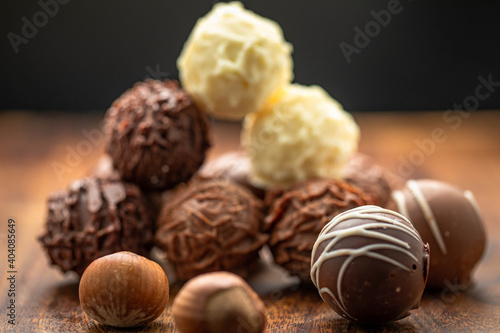 Mixed chocolate gourmet with nuts arranged in stack and photographed in white and brown wooden boards.