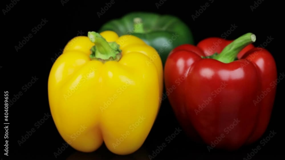 Three different colored bell peppers isolated against the black background. Red, yellow and green capsicums also known as bell peppers or sweet peppers rotating on a turntable - fresh vegetables Three different colored bell peppers isolated against the black background. Red, yellow and green capsicums also known as bell peppers or sweet peppers rotating on a turntable - fresh vegetables