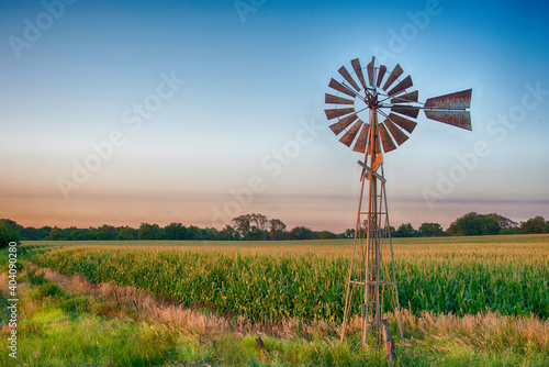 Vintage windmill at sunset with cornfield.