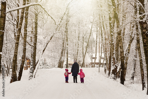 Mother with children walking through the winter forest. A path in the winter forest. Nature