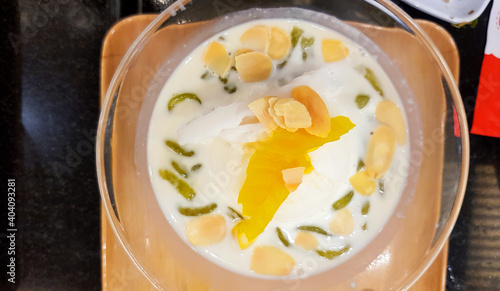 Top view of coconut milk ice cream with peanut, sliced jackfruit and Lod Chong in glass bowl. Flat lay of Thai dessert food on table. 