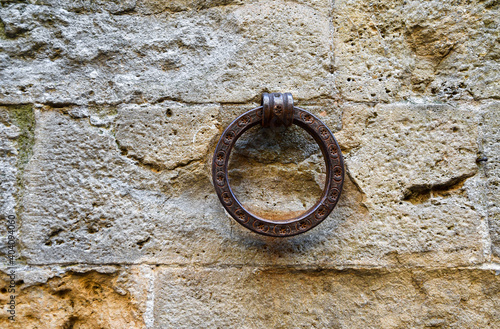 Close-up of a rusty wrought iron ring used in the past for tying horses on the stone wall of an old building, Tuscany, Italy