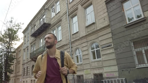 Wallpaper Mural Male backpacker in a yellow shirt walks at the crosswalk, looking at the old, ancient buildings at the old town. Young man tourist with backpack walking at the city Torontodigital.ca