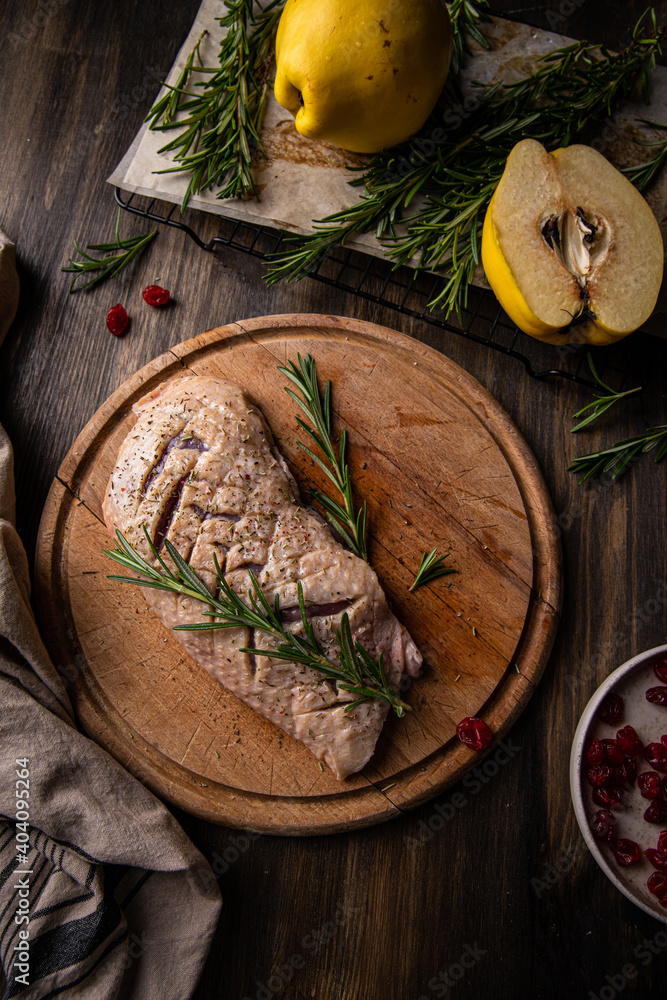 Raw duck breast, quince, rosemary and dried cranberries on wooden table. Raw duck breast, quince, rosemary and dried cranberries on wooden table.