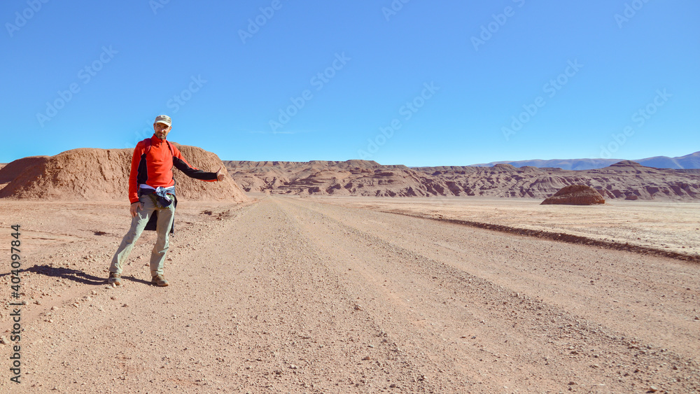 Man hitchhiking on a dirty road, in the desert of Puna highlands, Argentina