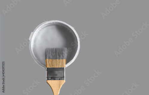 Can with paint of ultimate gray color and paintbrush on ultimate gray background