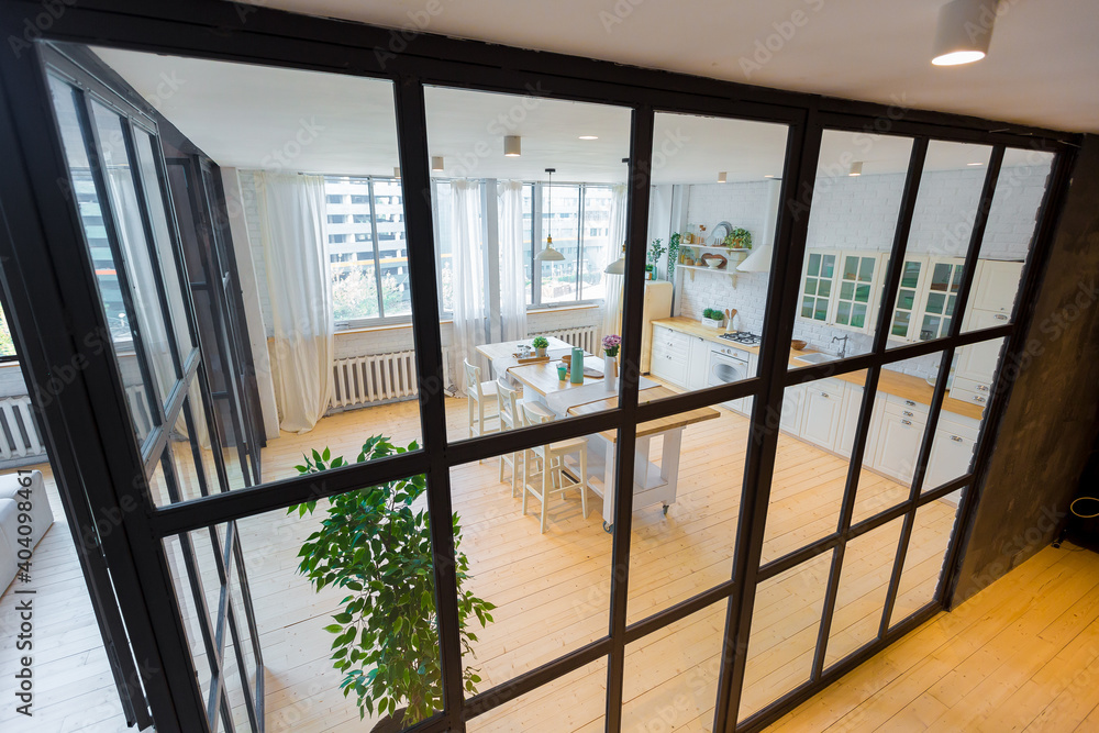 Stylish kitchen in light colors in a trendy modern duplex apartment with large high windows. Stylish kitchen in light colors in a trendy modern duplex apartment with large high windows.