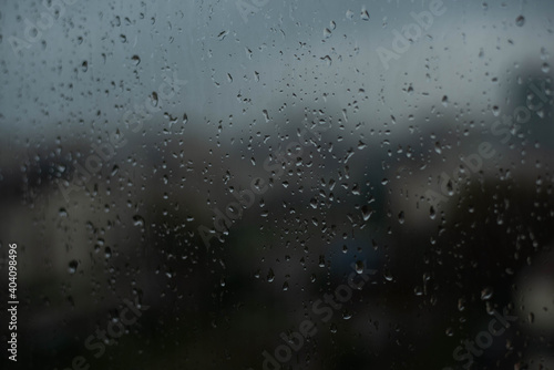 Rainy drops on window glass with blurry building background