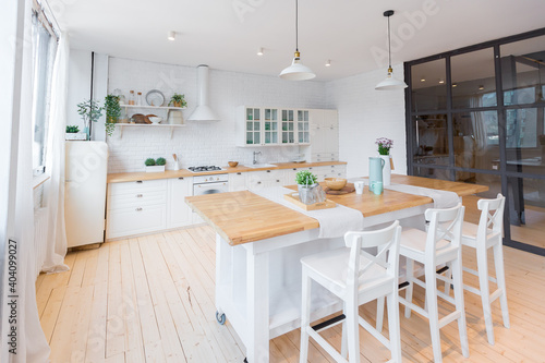 Stylish kitchen in light colors in a trendy modern duplex apartment with large high windows.