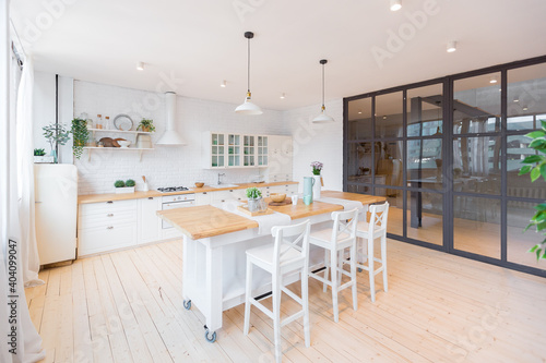 Stylish kitchen in light colors in a trendy modern duplex apartment with large high windows.