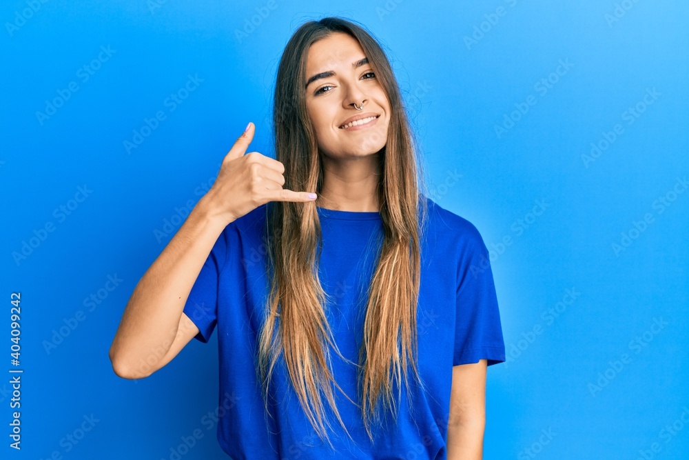 Young hispanic woman wearing casual clothes smiling doing phone gesture with hand and fingers like talking on the telephone. communicating concepts. Young hispanic woman wearing casual clothes smiling doing phone gesture with hand and fingers like talking on the telephone. communicating concepts.