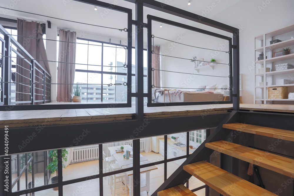 Obraz premium trendy modern design two-level apartment with large high windows. The stylish living room and kitchen in bright colors are undressed by a glass partition. bedroom on the second floor.