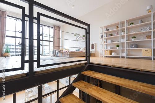 trendy modern design two-level apartment with large high windows. The stylish living room and kitchen in bright colors are undressed by a glass partition. bedroom on the second floor.