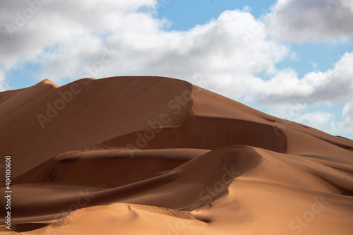 Golden sand dune 7 and white clouds on a sunny day in the Namib desert. Fantastic place for travelers